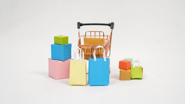 Carrinho em miniatura cheio de caixas coloridas e mini-bolsas isoladas no fundo branco