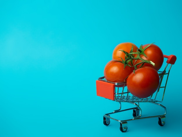 Carrinho pequeno com tomates em um fundo azul