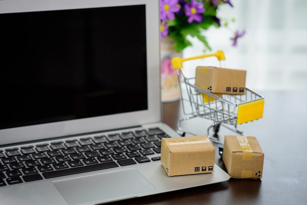 Foto el carrito del centro comercial y la pequeña caja de papel están vacíos en la computadora portátil. concepto de compra y venta de productos en línea.