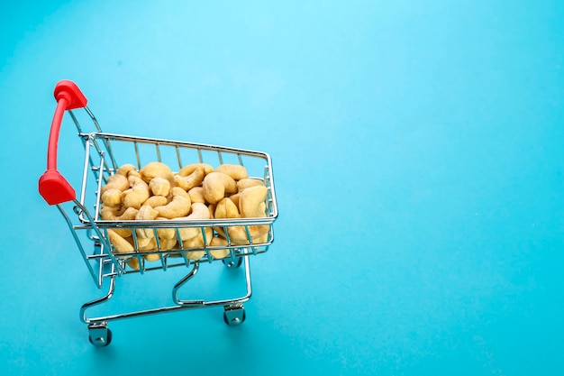 Carrito de comida lleno de anacardos pelados sobre una superficie azul