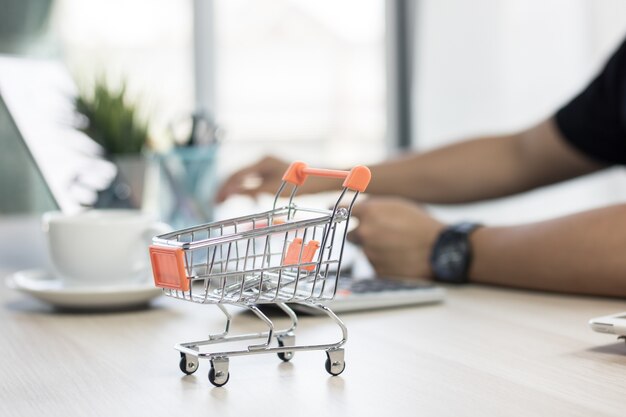 carrito de la compra y en la mesa con personas presionando el cuaderno para comprar y pagar en línea