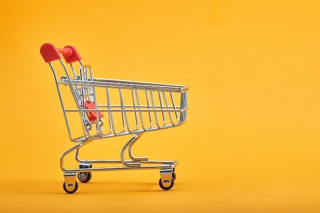 Carrito de la compra sobre fondo amarillo con algo de espacio de copia.