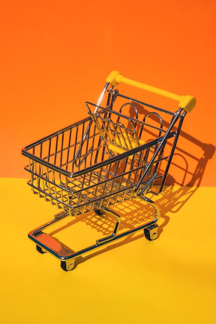 Foto carrito de la compra vacío sobre fondo amarillo anaranjado colorido copie el espacio para su texto