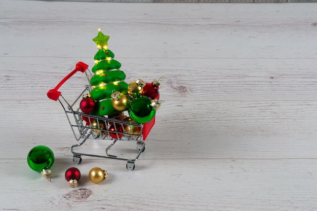 Carrito de compras con bolas de navidad y árbol con guirnaldas en los tableros de luces