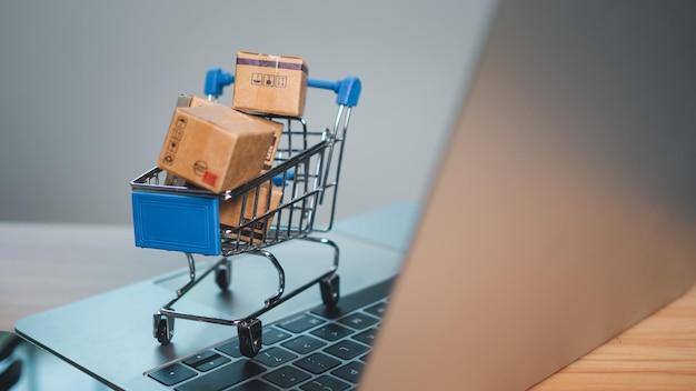 El carrito de compras y las cajas de productos colocadas en la computadora portátil representan el concepto de compras en línea