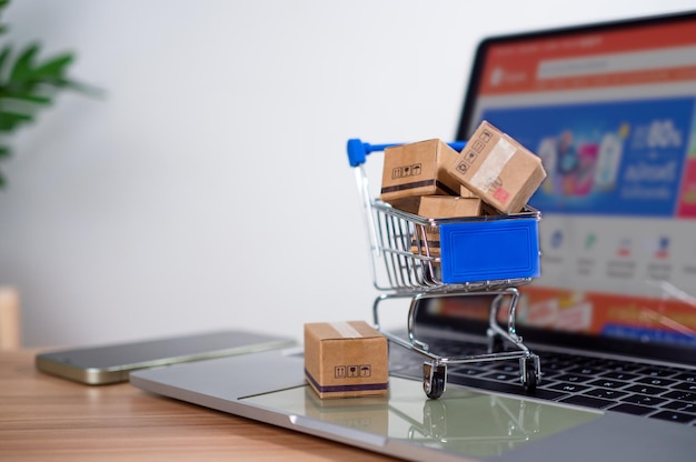 El carrito de compras y las cajas de productos colocadas en la computadora portátil representan el concepto de compras en línea