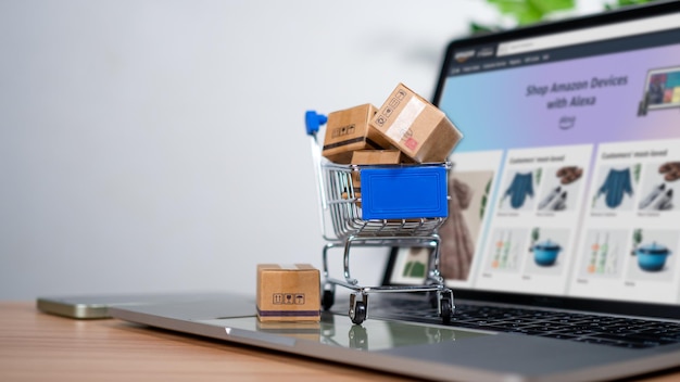 El carrito de compras y las cajas de productos colocadas en la computadora portátil representan el concepto de compras en línea