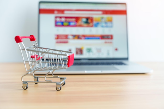 Carrito de compras y computadora portátil con sitio web de mercado tecnología comercial comercio electrónico banca digital y concepto de pago en línea