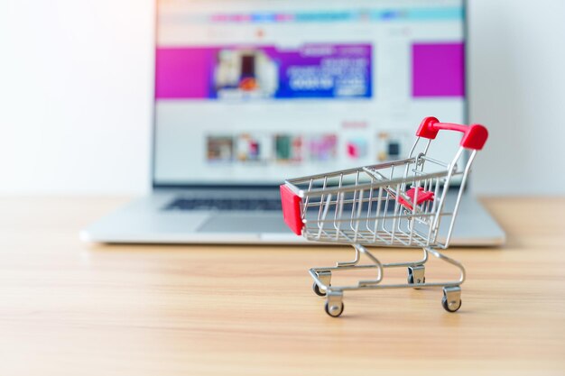 Carrito de compras y computadora portátil con sitio web de mercado tecnología comercial comercio electrónico banca digital y concepto de pago en línea