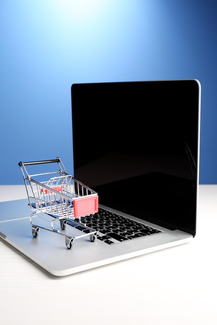 Foto carrito de compras en la computadora portátil sobre la mesa sobre fondo azul