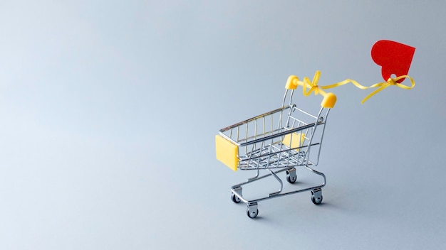 Carrito de compras con corazón sobre fondo gris Plantilla de promoción y comprasDía de San ValentínCopiar espacio