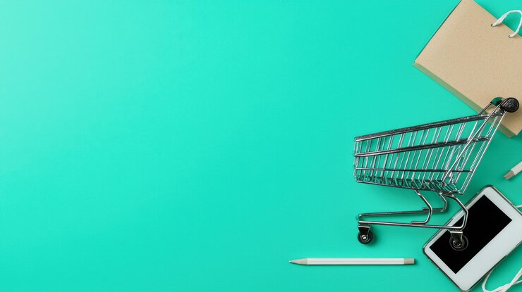 Un carrito de compras está en un fondo verde con un teléfono celular y un bolígrafo