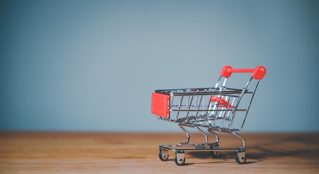 Carrito de compras en mesa de madera fondo azul Concepto mercado de comercio electrónico comprar o comprar comestibles tienda en línea negocio minorista consumidor cesta vacía servicio de envío pago de pedido