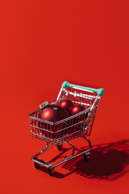 Carrito de compras de navidad con bolas de adornos de navidad rojas sobre fondo rojo navidad mínima