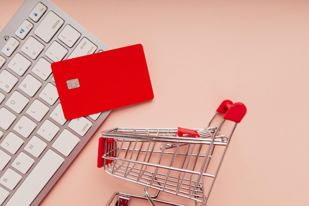 Carrito de compras y tarjeta de crédito roja con un primer plano del teclado Concepto de compras en línea