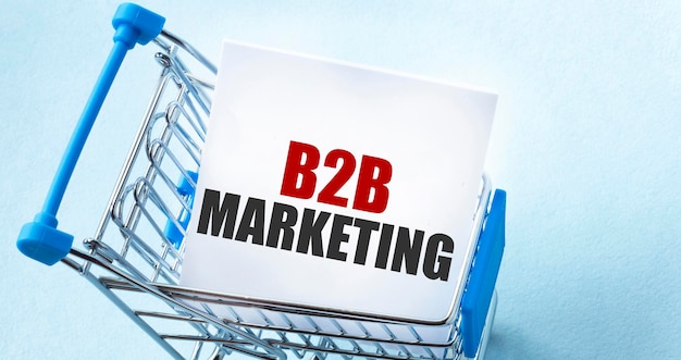 Carrito de compras y texto de marketing b2b en papel blanco Lista de notas Concepto de lista de compras en fondo azul