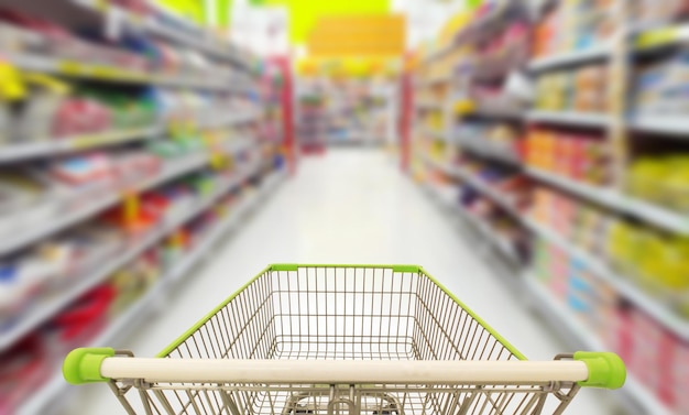 Un carrito de compras en una tienda de comestibles con un estante al fondo.