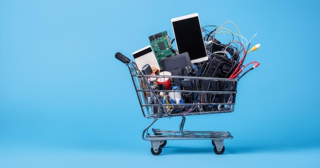 Foto un carrito lleno de productos electrónicos aislados en un fondo azul copia espacio de fondo