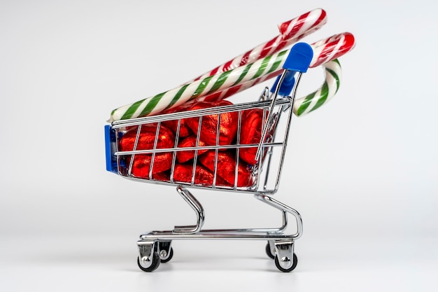 Un carrito de supermercado cargado de dulces y bastones de caramelo de Navidad