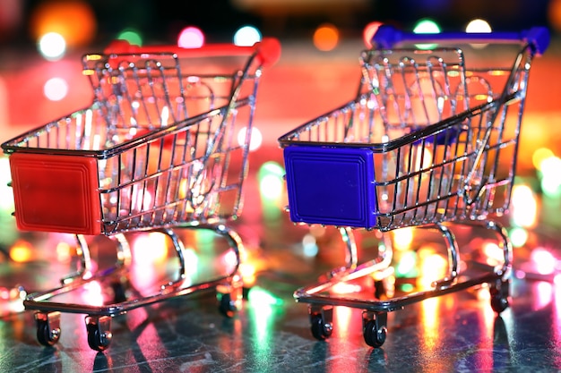 Carrito de supermercado de metal sobre un fondo de luces de colores