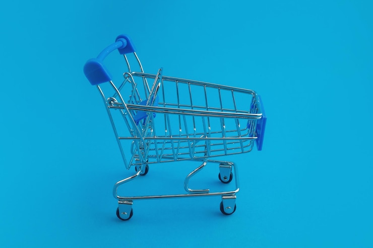 Foto carrito de supermercado sobre fondo azul.