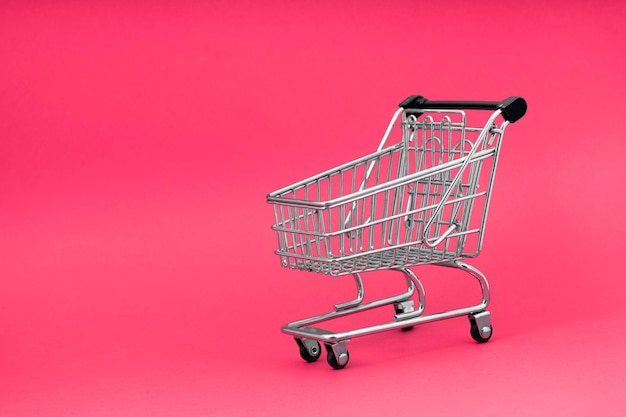 El carrito de la tienda de la carretilla negra sobre el diseño de fondo rosa para el viernes negro