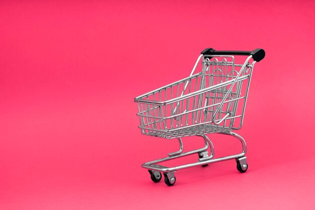 El carrito de la tienda de la carretilla negra sobre el diseño de fondo rosa para el viernes negro