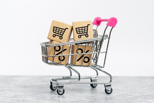 carritos de supermercado con carrito de compras, icono de porcentaje en cubos de madera. concepto de compras.