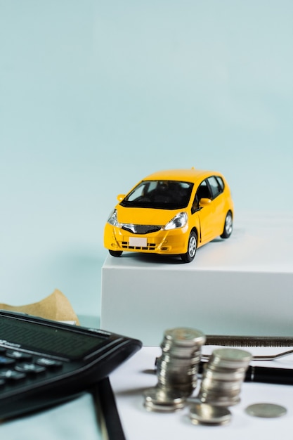 Carro amarelo focado com calculadora e moedas