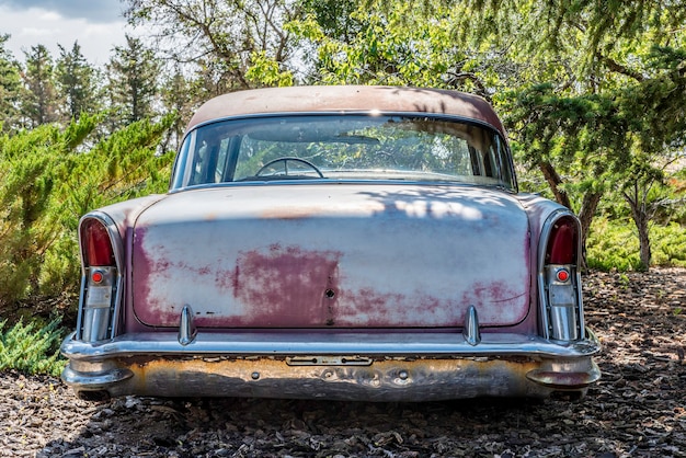 Carro antigo abandonado cercado por árvores nas pradarias de saskatchewan, no canadá