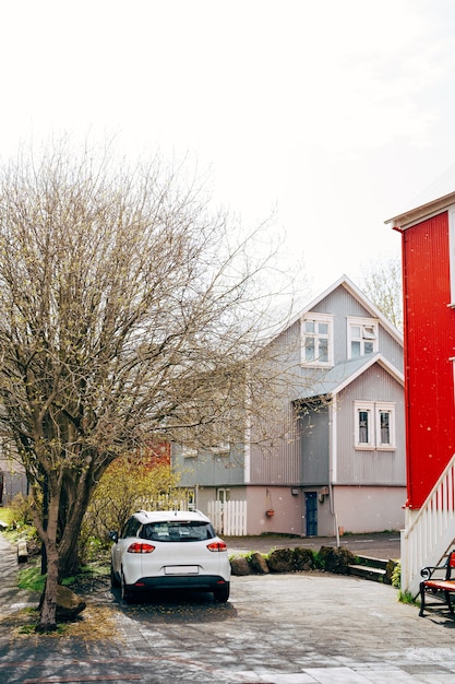 Carro branco estacionado em frente à casa na rua de reykjavik, capital da islândia