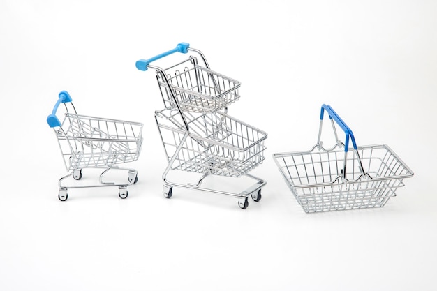 Carro y canasta para compras en el mercado de comestibles sobre fondo blanco.