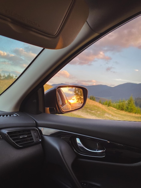 Carro cinza perto de uma grande faia velha nas montanhas ao pôr do sol