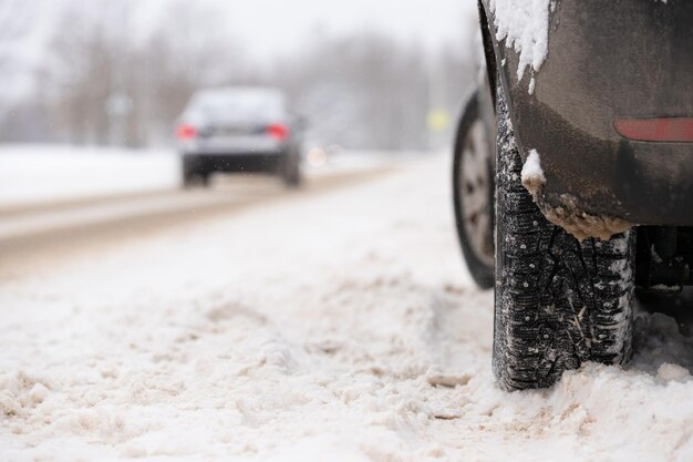 Carro coberto de neve com rodas cravejadas estacionado ao lado da estrada em um dia frio de inverno