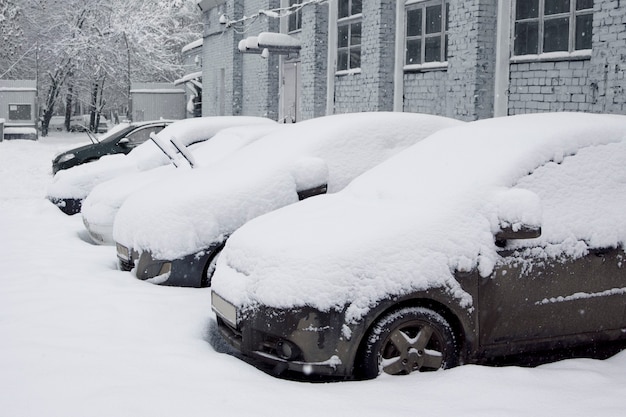 Carro coberto de neve no estacionamento. Cena urbana. Depois de uma tempestade de neve. Limpe o automóvel da neve.