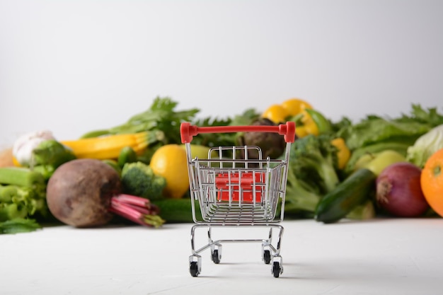 Carro de la compra y diferentes frutas y verduras frescas para el diseño Surtido de frutas y verduras frescas Fondo de alimentos saludables Compras de alimentos en el supermercado