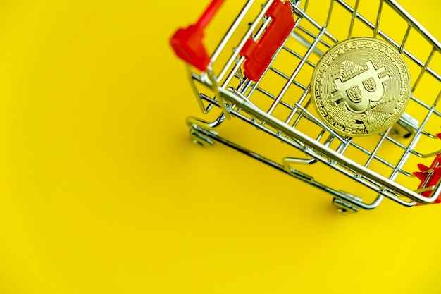 Carro de compras en amarillo con bitcoin insidel. Símbolo del comercio electrónico