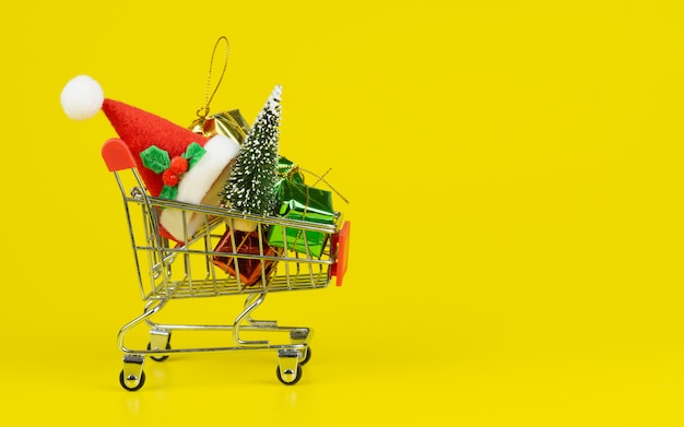 Carro de compras con árbol de navidad y cajas de regalo en miniatura sobre fondo amarillo