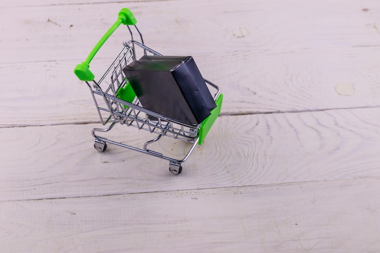 Foto carro de compras con caja negra sobre fondo blanco de madera