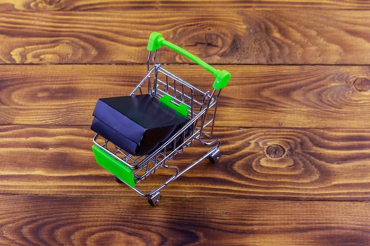 Foto carro de compras con caja negra sobre fondo de madera