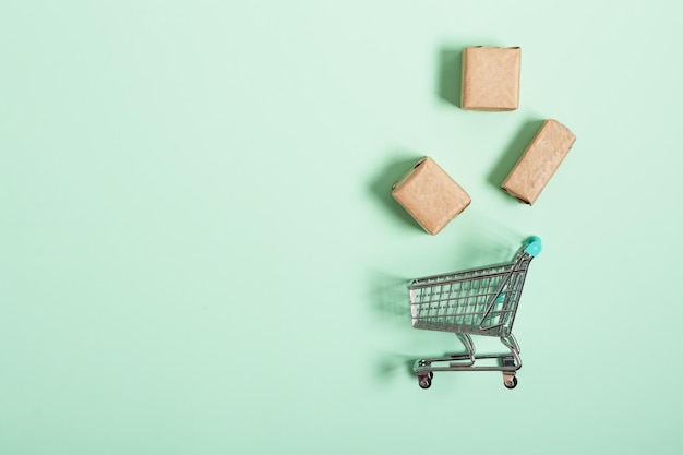 Carro de compras con cajas de paquetes sobre fondo verde