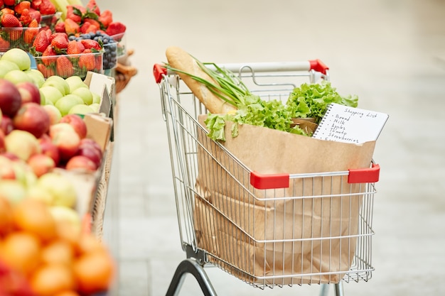 Carro de compras con comestibles frescos en el supermercado, sin gente