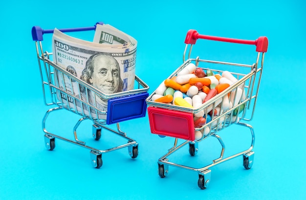 Carro de compras completo con pastillas y carro de compras con dinero sobre fondo azul Concepto de farmacia