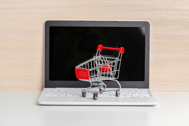 Carro de compras en la computadora portátil en la mesa de madera