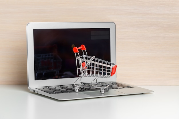 Carro de compras en la computadora portátil en la mesa de madera