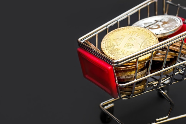 Carro de compras decorativo con monedas de bitcoins en negro Cerrar el concepto de comercio electrónico y negocios