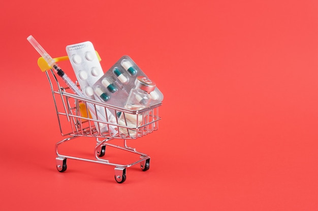 Carro de compras con medicina en superficie roja