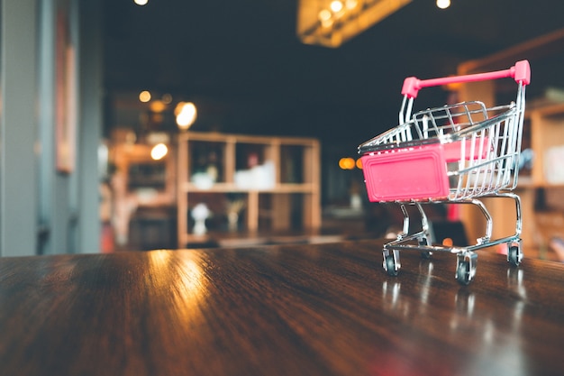 Carro de compras en la mesa de madera en la tienda, las compras en línea y el concepto de comercio electrónico.