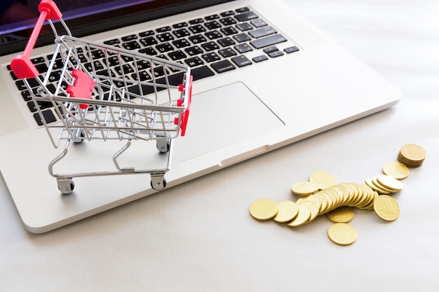 Foto carro de compras con moneda de oro y cuaderno.