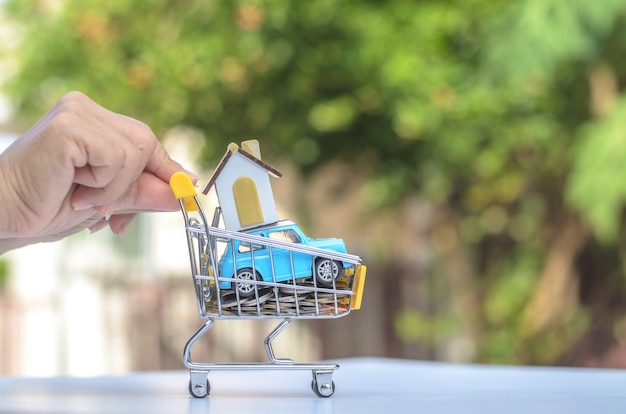 Foto carro de compras con monedas, casa, coche para comercio minorista. uso de imágenes para compras en línea, lugar de marketing en todo el mundo, concepto de negocio.